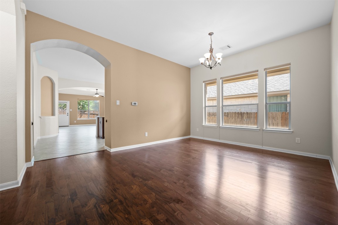 216 Archipelago Trail Austin, TX 78717 - Photo 8 of 40 Empty room with arched walkways, dark wood finished floors, ceiling fan, and a chandelier