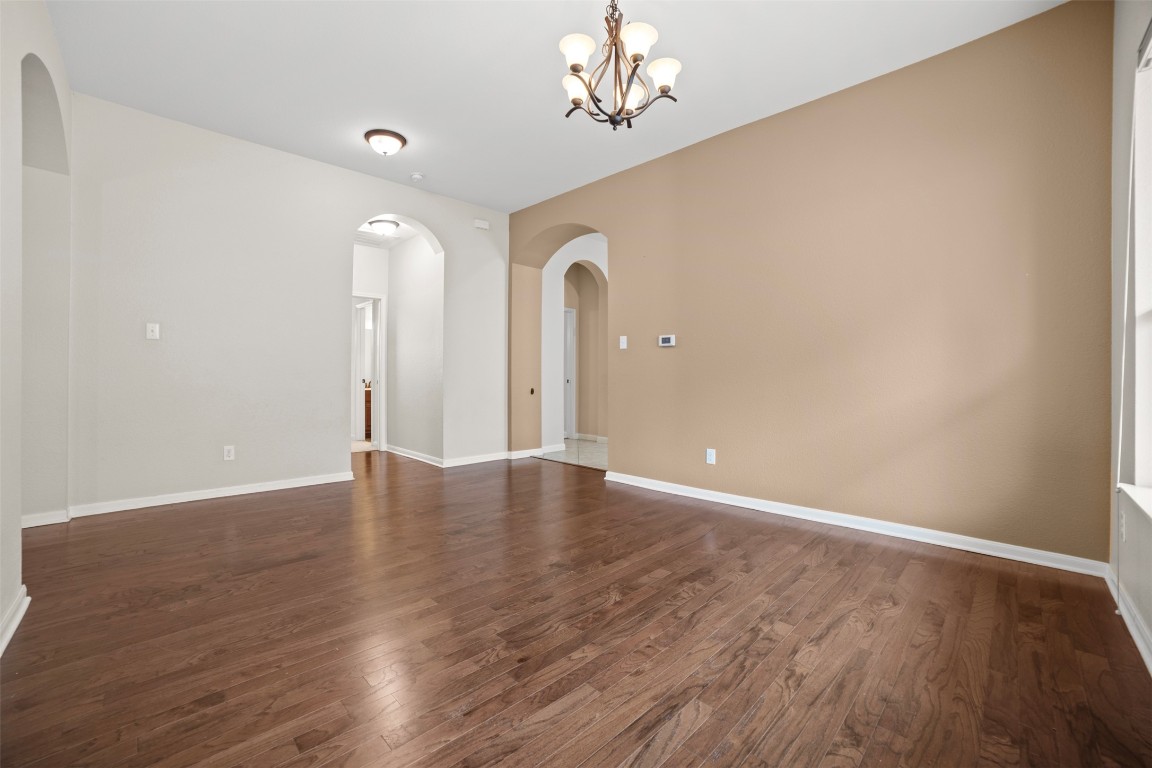216 Archipelago Trail Austin, TX 78717 - Photo 9 of 40 Spare room featuring arched walkways, dark wood-style floors, and a chandelier