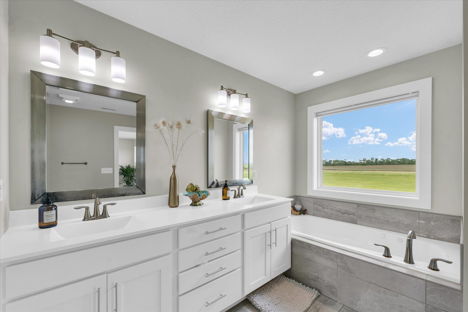 1908 Littlefield Lane Mahomet, IL 61853 - Photo 28 of 51 a bathroom with double vanity sinks a large mirror and a bathtub