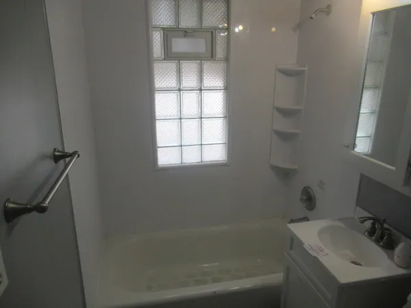a bathroom with a tub sink vanity granite and shower