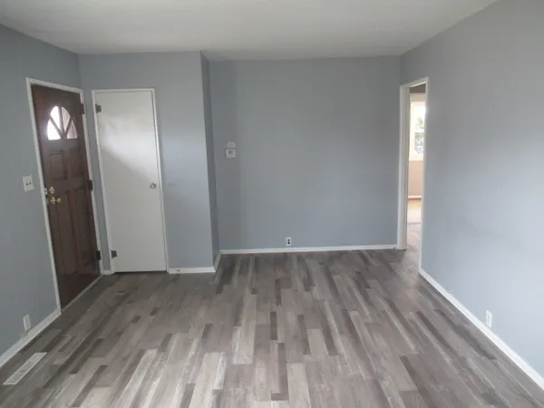 an empty room with wooden floor and mirror