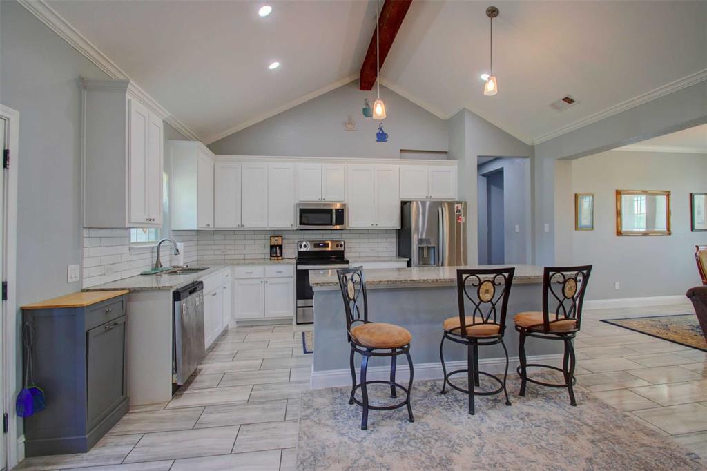 8789 Hutcheson Hill Road Springtown, TX 76082 - Photo 8 of 32 a kitchen with stainless steel appliances kitchen island granite countertop a sink and cabinets