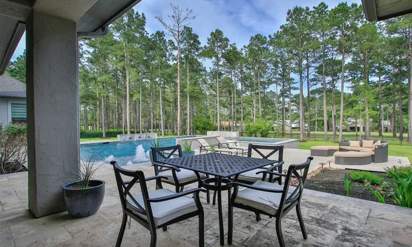 a view of pool with lawn chairs and plants