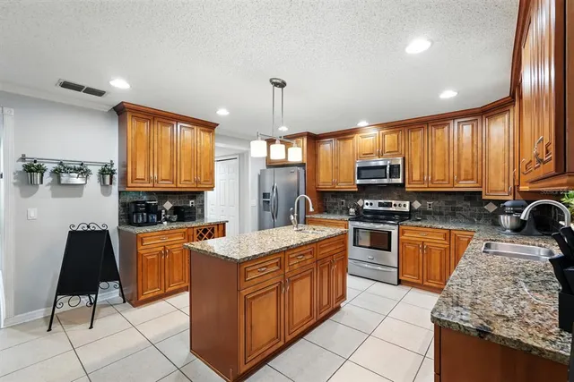 a kitchen with granite countertop wooden cabinets stainless steel appliances a sink and a window