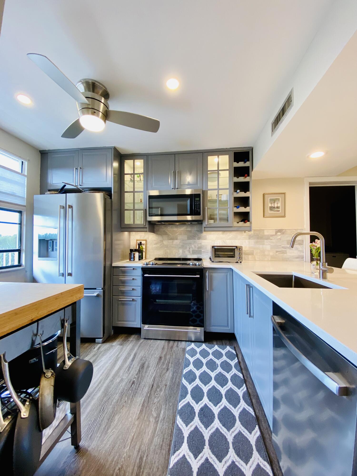 a large kitchen with stainless steel appliances wooden floor a stove and a sink
