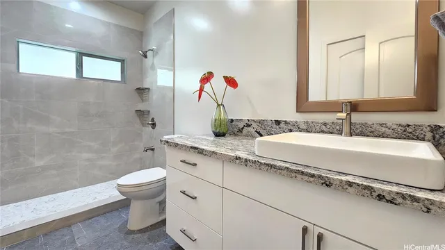 a bathroom with a granite countertop sink a toilet and a mirror