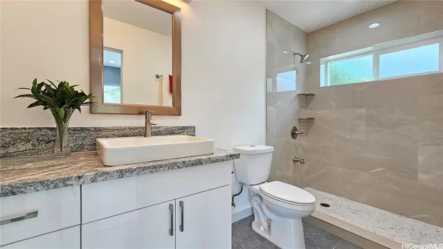 a bathroom with a granite countertop sink a toilet and a mirror