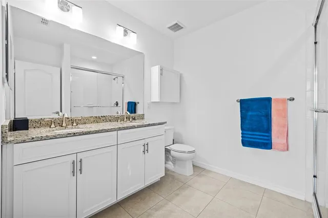 a bathroom with a granite countertop toilet sink and mirror