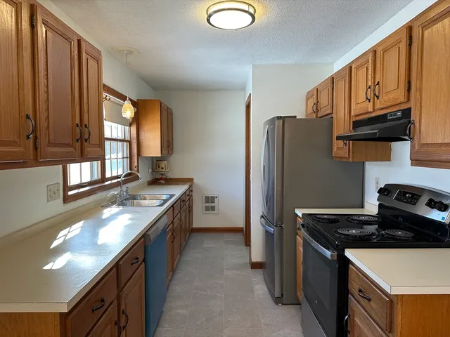a kitchen with granite countertop a stove sink and refrigerator