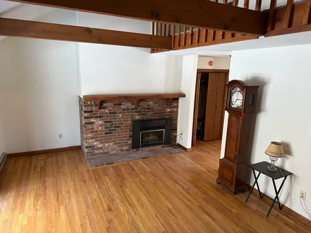 a view of empty room with wooden floor and fireplace