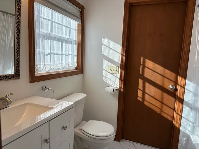 a bathroom with a granite countertop toilet sink and mirror