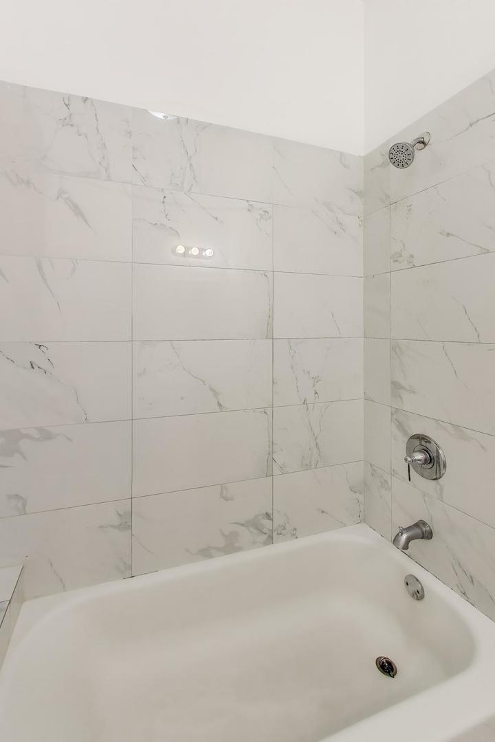 1908 West 48th Street, Unit 1R Chicago, IL 60609 - Photo 14 of 17 a white bath tub sitting next to a white sink and vanity