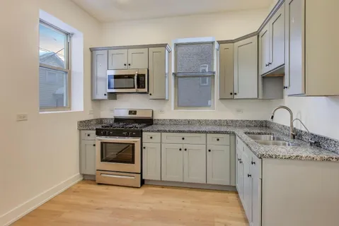 a kitchen with granite countertop a sink stove and microwave