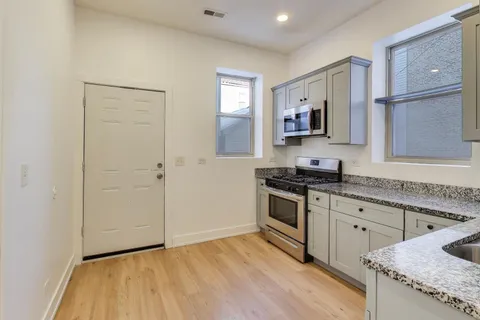 a kitchen with granite countertop a stove top oven and cabinets