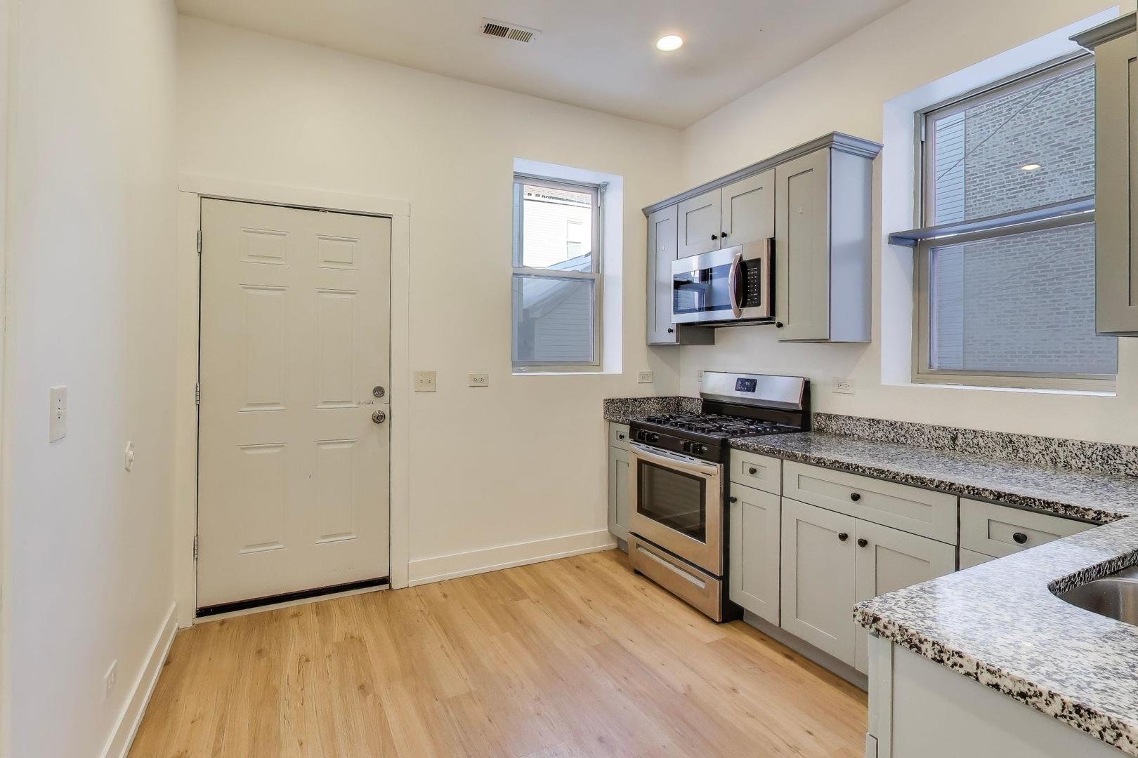 1908 West 48th Street, Unit 1R Chicago, IL 60609 - Photo 8 of 17 a kitchen with granite countertop a stove top oven and cabinets