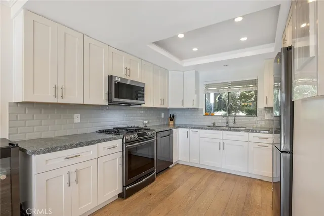 a kitchen with granite countertop white cabinets and stainless steel appliances