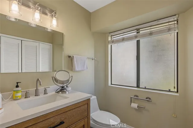 a bathroom with a granite countertop sink toilet and a mirror