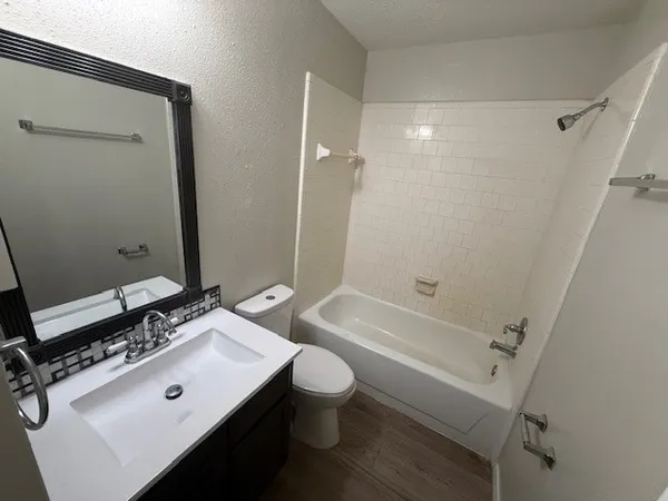 a bathroom with a bathtub shower sink vanity mirror and toilet