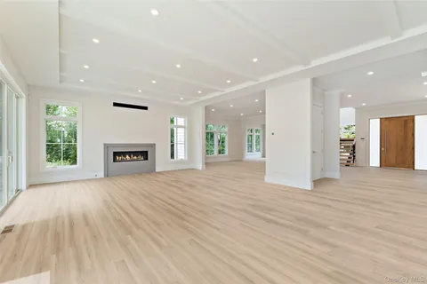 an empty room with wooden floor fireplace and windows