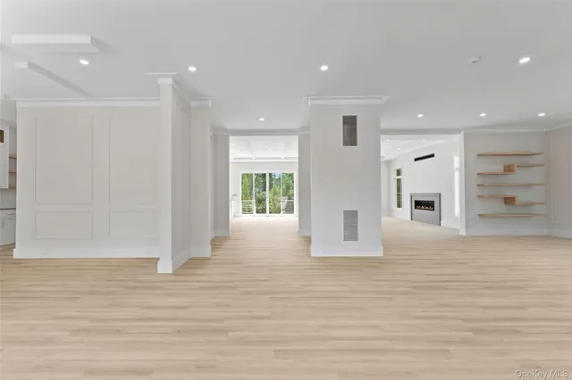 a view of an empty room with wooden floor and windows