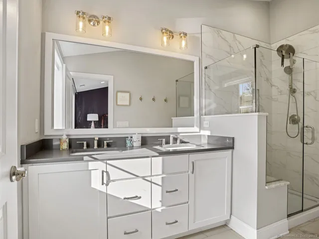 a bathroom with a double vanity sink mirror and shower