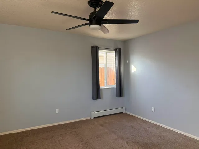 an empty room with a window and a fan