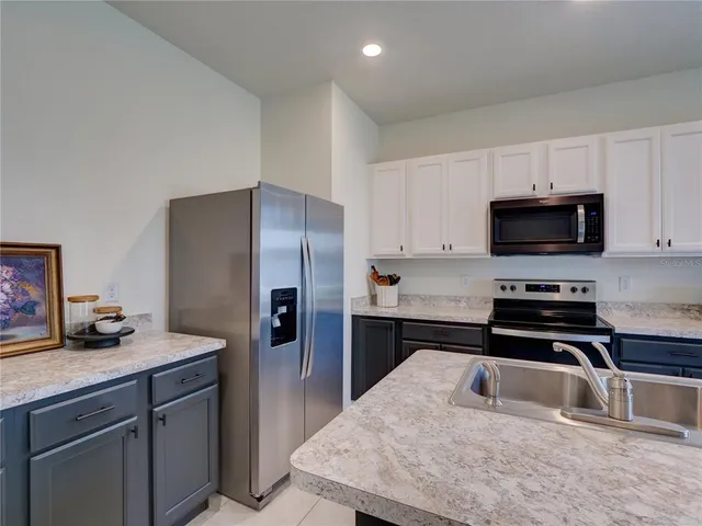 a kitchen with sink a microwave a refrigerator and cabinets