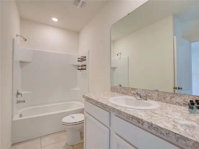 a bathroom with a granite countertop sink a toilet and bathtub