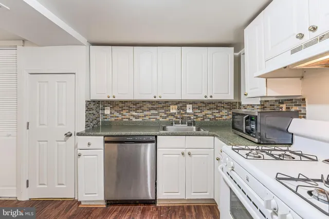 a kitchen with stainless steel appliances granite countertop a stove a sink and white cabinets