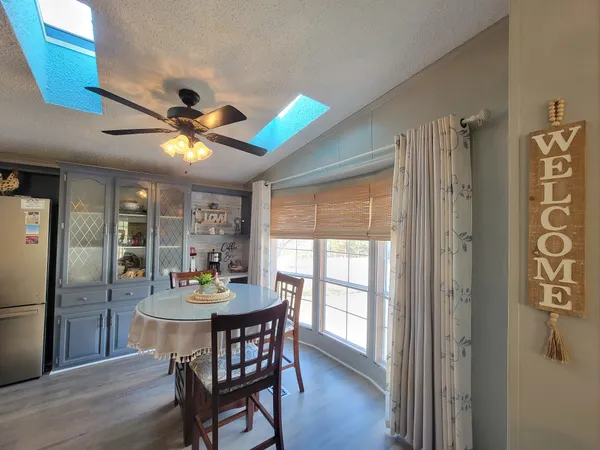 a kitchen with stainless steel appliances granite countertop a dining table chairs refrigerator and microwave