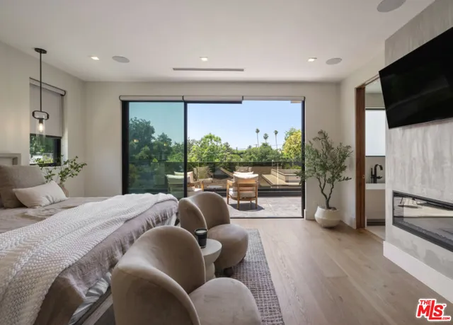 a bedroom with furniture a flat screen tv and a large window