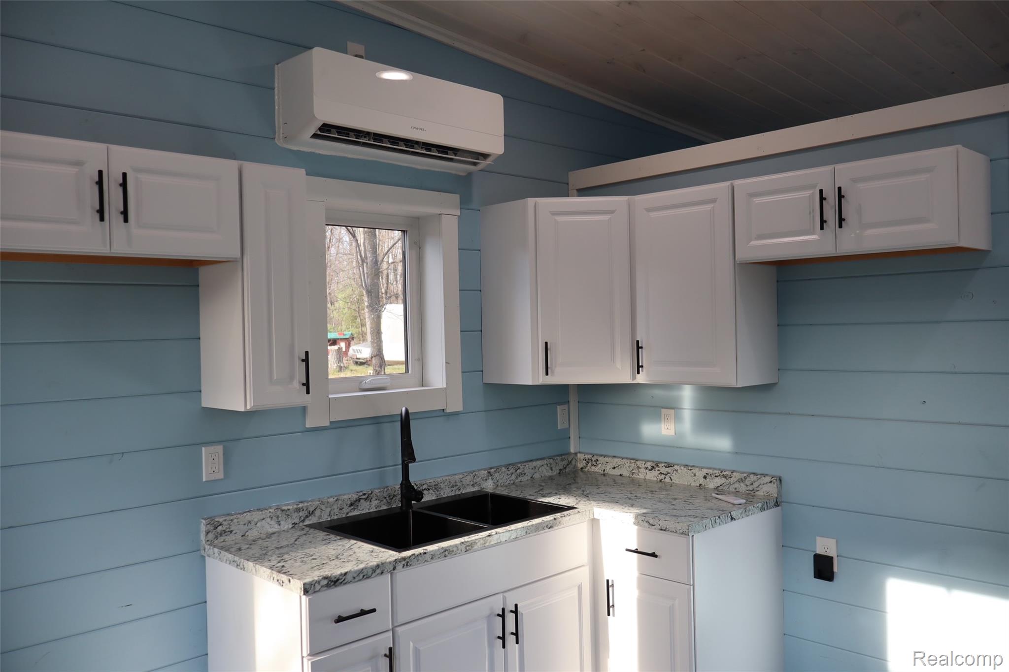 1545 South La Chance Road Lake City, MI 49651 - Photo 41 of 51 Kitchen with wooden walls, white cabinetry, light stone counters, and a vaulted wooden ceiling