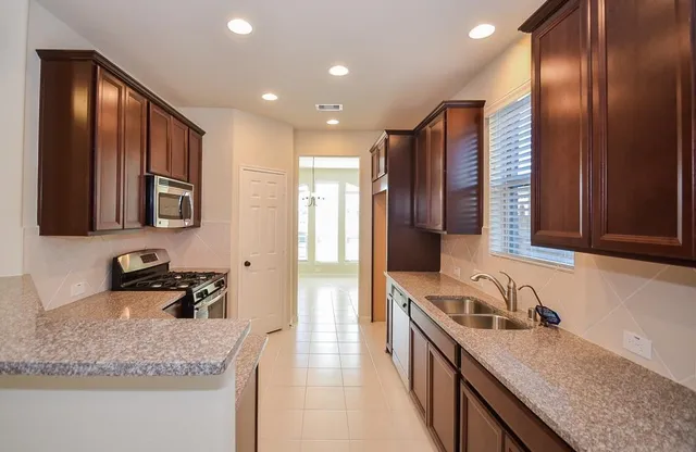 a kitchen with stainless steel appliances granite countertop a sink stove and cabinets