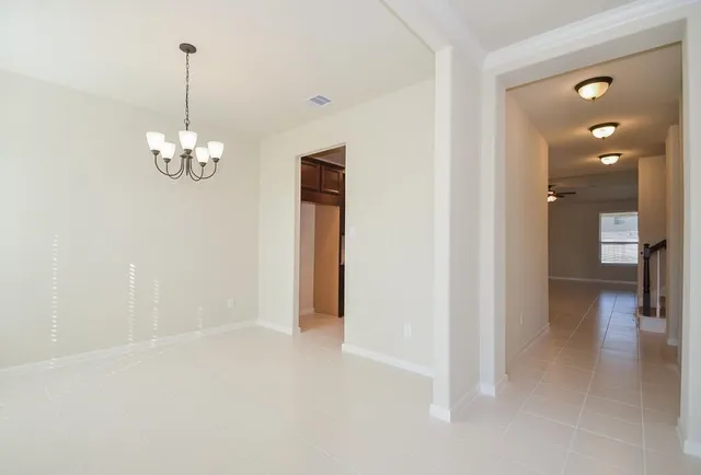 a view of a hallway with chandelier and glass door