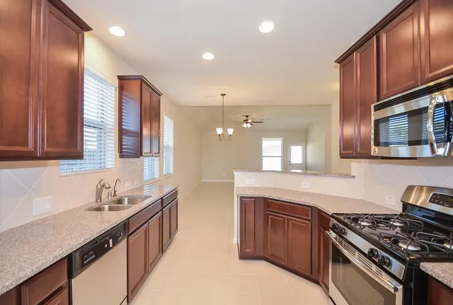 a kitchen with stainless steel appliances granite countertop a stove a sink and a microwave