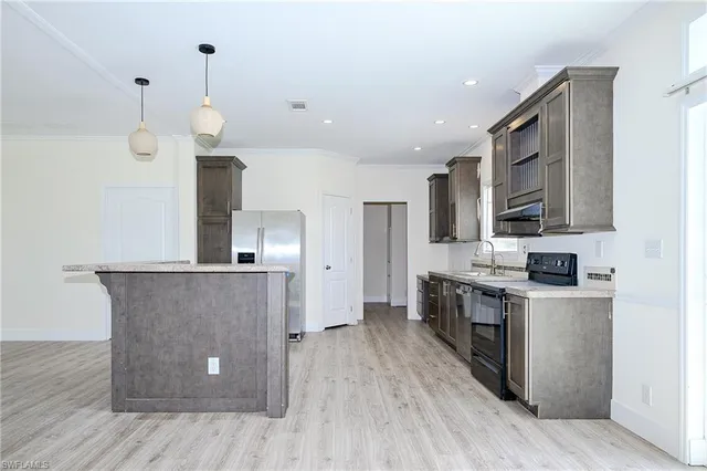 a large kitchen with stainless steel appliances a large counter top and wooden floors