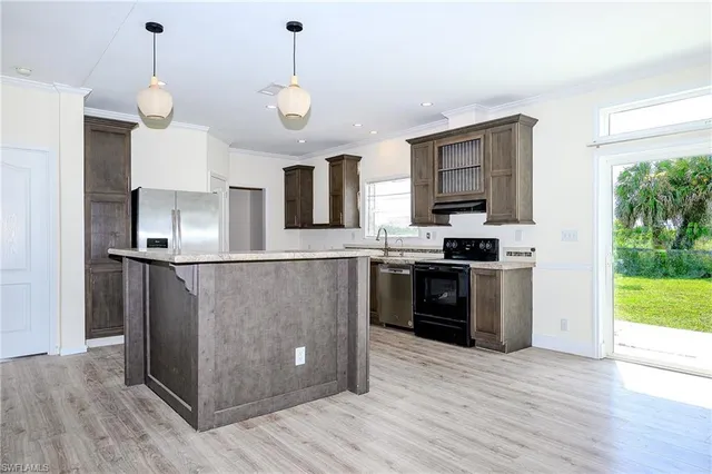 a kitchen with stainless steel appliances granite countertop a refrigerator a stove a sink dishwasher and a oven with wooden floor