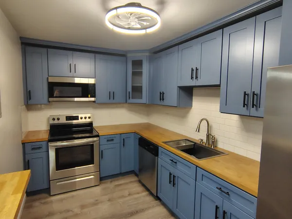 a kitchen with stainless steel appliances a sink a stove and cabinets