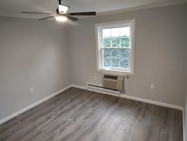 an empty room with wooden floor fan and windows