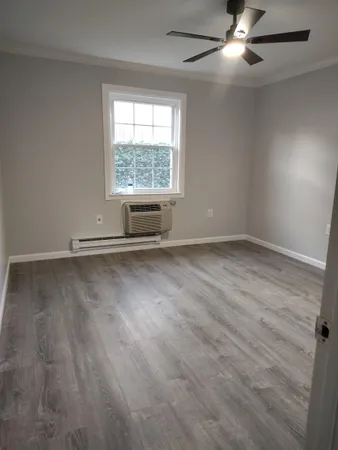 an empty room with wooden floor fan and windows