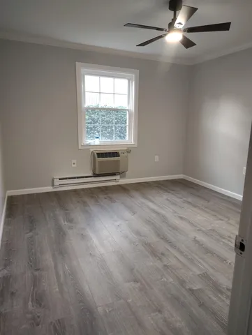 an empty room with wooden floor fan and windows