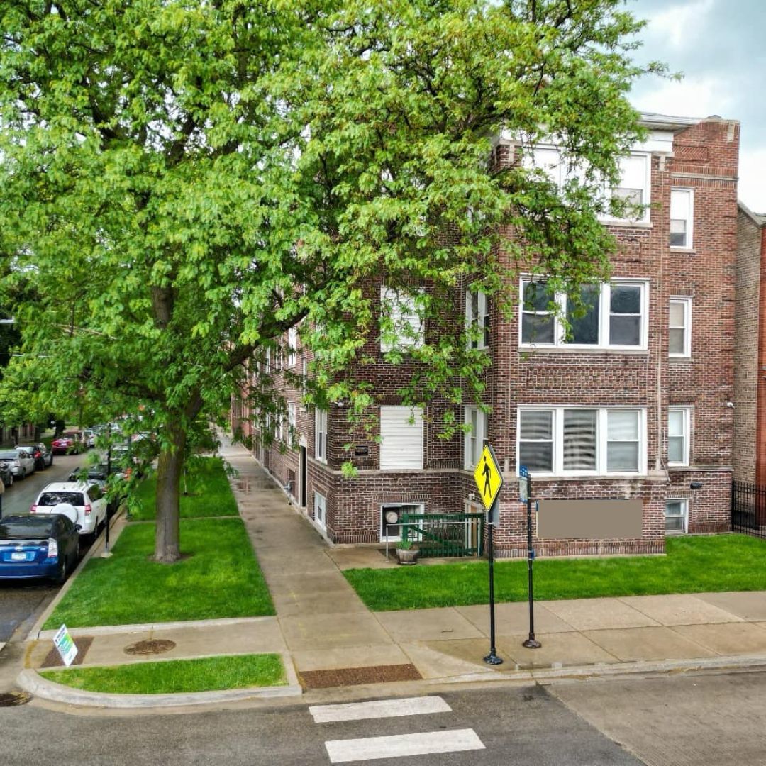 a view of a brick house with a yard and large trees