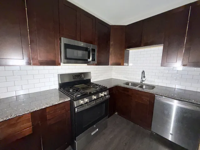 a kitchen with granite countertop stainless steel appliances a sink stove and microwave