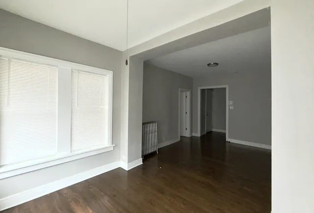 a view of an empty room with wooden floor and closet