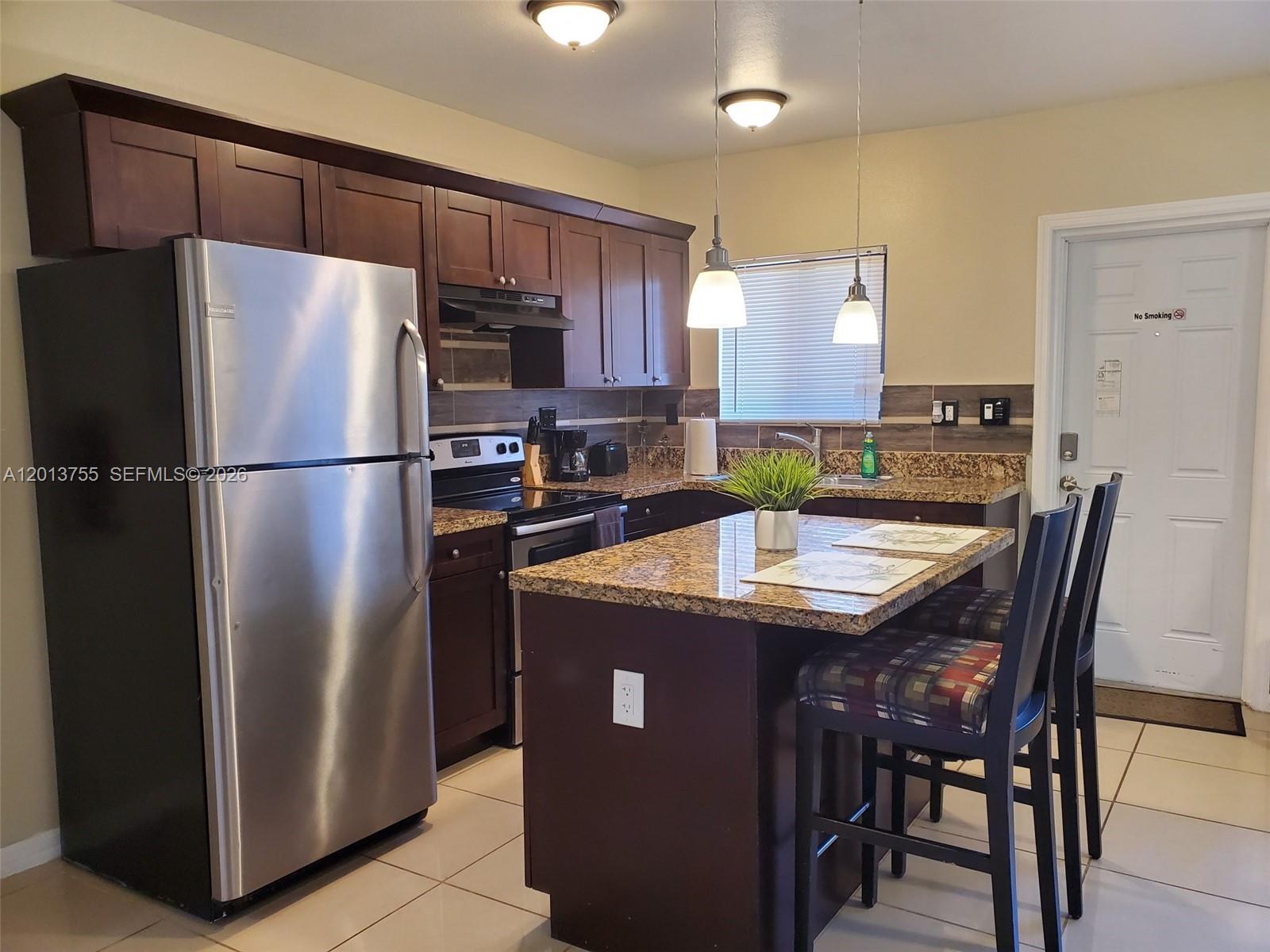 a kitchen with stainless steel appliances granite countertop a refrigerator a stove a sink a dining table and chairs