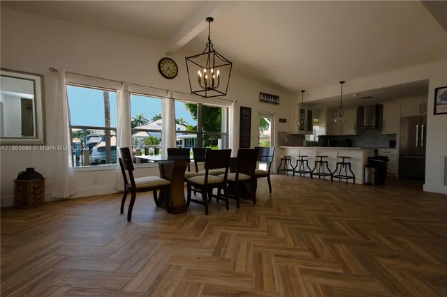 a view of a dining room and livingroom with furniture wooden floor a rug a fireplace and a chandelier