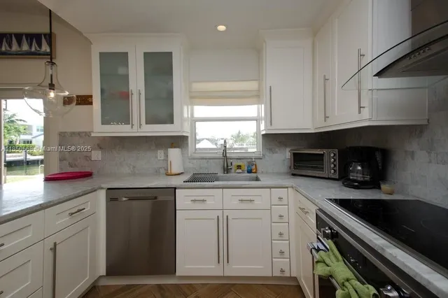 a kitchen with granite countertop a sink stainless steel appliances and cabinets