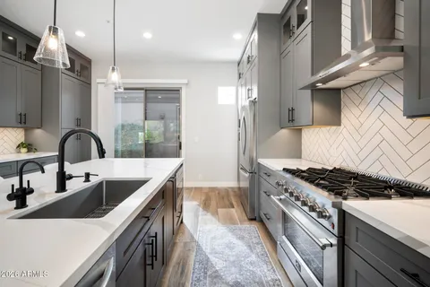 a large kitchen with stainless steel appliances kitchen island granite countertop a table chairs in it and wooden floors