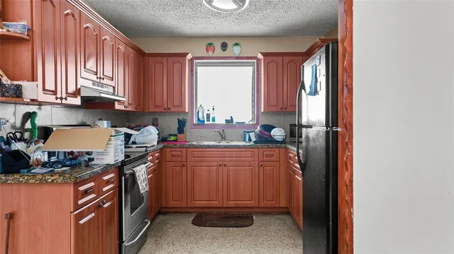 a kitchen with stainless steel appliances granite countertop a stove a sink and a refrigerator