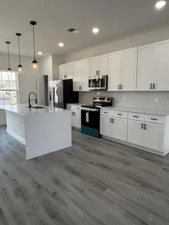 a large kitchen with stainless steel appliances kitchen island a large counter top and a stove top oven